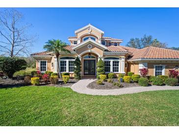 Stunning two-story home with a tile roof, manicured lawn, and lush landscaping under a clear blue sky at 6919 Winners Cir, Lakewood Ranch, FL 34202