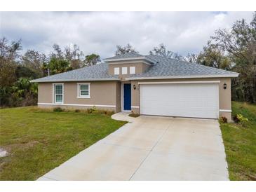 Charming single Gathering house featuring a two-car garage, light tan exterior, and blue front door at 1765 Jagust Rd, North Port, FL 34288