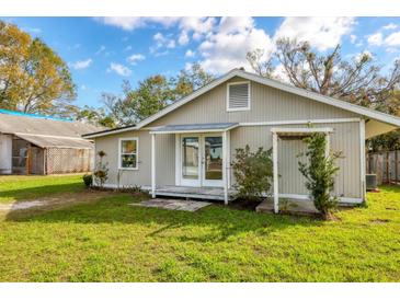 Quaint home featuring a grassy backyard, covered porch, and lush landscaping at 1004 12Th W Ave, Palmetto, FL 34221