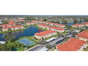 Beautiful aerial view of the condo complex with a tennis court, lake, and red-tiled roofs at 1005 Villagio Cir # 106, Sarasota, FL 34237