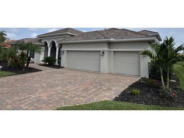 Attractive home showing the three car garage, beautiful brick driveway and tropical landscaping at 10509 Winding Stream Way, Bradenton, FL 34212
