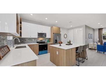 Bright kitchen features modern appliances, breakfast bar, and white and wood cabinetry at 1313 Kacerik St, North Port, FL 34288