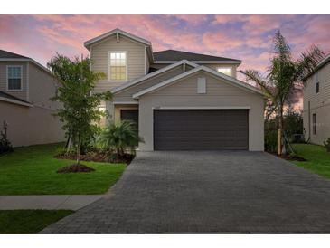 Charming two-story home featuring a spacious garage, a well-manicured lawn, and a beautiful brick driveway at 13977 Lilac Sky Ter, Bradenton, FL 34211