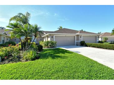 Charming home featuring a well-manicured lawn, colorful flowerbeds, and a convenient two-car garage at 5283 Chase Oaks Dr, Sarasota, FL 34241