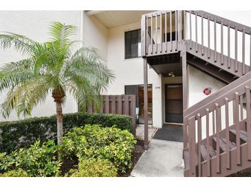 Inviting condo exterior featuring a well-manicured lawn, mature palm tree, and private entrance stairs at 2774 71St St Ct W # 2101, Bradenton, FL 34209