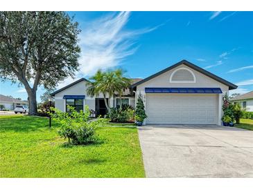 Charming single-story home with a well-manicured lawn, mature tree, and a two-car garage at 279 Park Forest Blvd, Englewood, FL 34223
