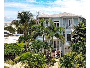 Charming two-story home with a turquoise exterior, lush landscaping and a private balcony, perfect for coastal living at 130 50Th St, Holmes Beach, FL 34217