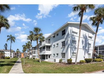 Well-maintained condo building with manicured lawn and tropical palm trees under a bright blue sky at 5922 Garden Ln # A31, Bradenton, FL 34207
