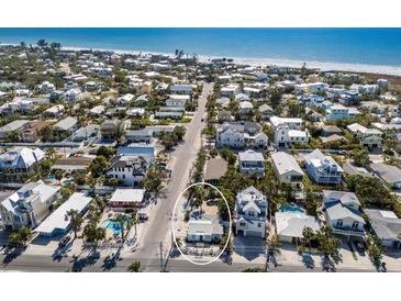 Aerial view of a charming coastal community with a beach, and white home near the ocean at 701 N Bay Blvd, Anna Maria, FL 34216