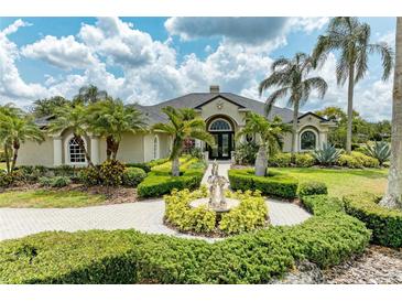 Stunning home exterior featuring lush landscaping, a circular driveway, and a beautiful water fountain at 10002 Cherry Hills Avenue Cir, Bradenton, FL 34202