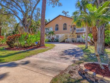 Charming two-story home with arched windows, brick driveway, lush landscaping and beautiful mature trees at 7717 27Th W Ave, Bradenton, FL 34209