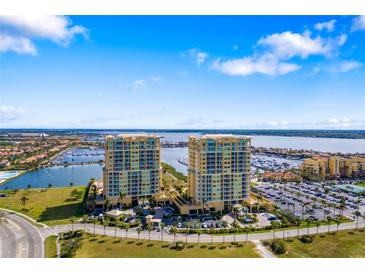 Stunning aerial view of two luxury condo buildings overlooking a marina with waterfront views and parking at 130 Riviera Dunes Way # 1201, Palmetto, FL 34221