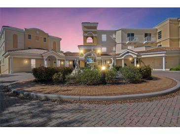 Stunning building exterior featuring a landscaped roundabout, tile roof, and neutral color palette at 14021 Bellagio Way # 309, Osprey, FL 34229