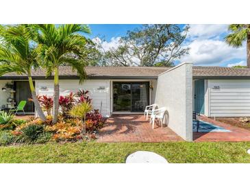 Inviting front patio with brick pavers and lush tropical landscaping by the front door and sliding glass door at 3503 Longmeadow # 2, Sarasota, FL 34235