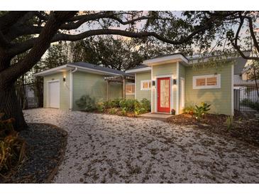Charming single-story home with a landscaped yard, gravel driveway, and a vibrant red front door at 3521 Almeria Ave, Sarasota, FL 34239