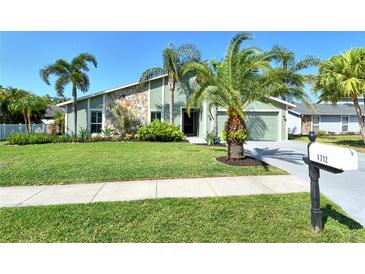 Charming home with lush lawn, lovely palms and stone accents creating inviting curb appeal at 4712 Glenbrooke Dr, Sarasota, FL 34243