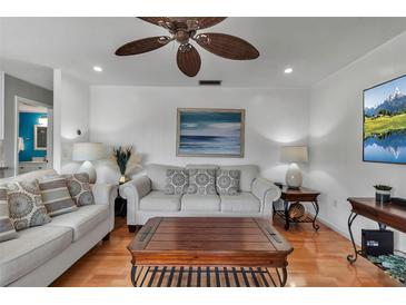 Bright living room with white sofas, ceiling fan, hardwood floors and stylish decor at 5955 Midnight Pass Rd # 18E, Sarasota, FL 34242