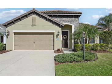 Charming home exterior featuring a stone facade, two-car garage, and well-maintained landscaping at 1604 Still River Dr, Venice, FL 34293
