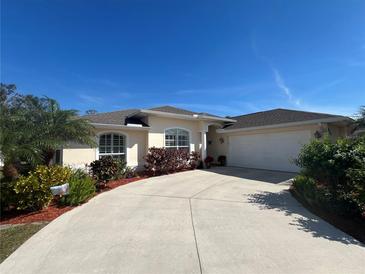 Charming home with a manicured lawn, lush landscaping, and a long driveway leading to a two-car garage at 4224 Hall St, Port Charlotte, FL 33948
