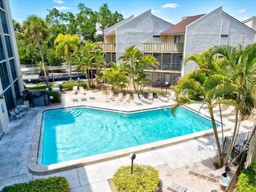 Aerial view of a community pool surrounded by lush landscaping and lounging area at 6157 Midnight Pass Rd # E42, Sarasota, FL 34242