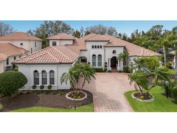 Stunning exterior showcasing a tile roof, lush landscaping, and a beautiful brick driveway at 7210 Desert Ridge Gln, Lakewood Ranch, FL 34202