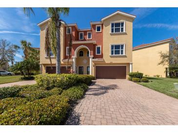 Inviting two-story villa with a terracotta roof, colorful facade, two car garage, and well-maintained front yard landscaping at 1318 3Rd Street E Cir, Palmetto, FL 34221