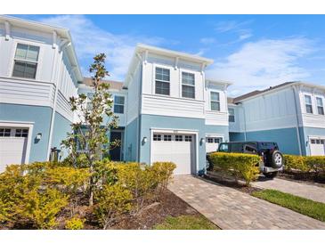 Charming two-story home featuring a one car garage, brick paved driveway, blue siding and well-manicured landscaping at 4091 Via Sienna Cir, Sarasota, FL 34243