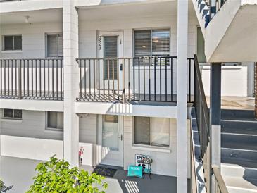 Condo building exterior featuring second story unit entrance with gray railings and gray stairway at 5907 Garden Ln # H26, Bradenton, FL 34207