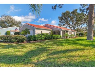 Charming single-story home featuring a red tile roof, lush landscaping, and a well-maintained lawn at 7202 Las Casas Dr # 7202, Sarasota, FL 34243