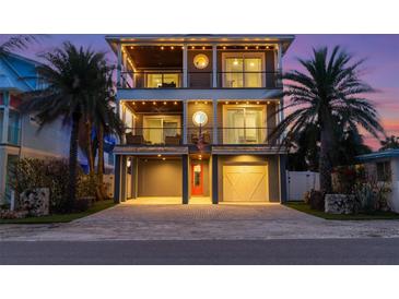 Charming three-story home with dual balconies, a brick driveway, and well-manicured palm trees at 108 Magnolia Ave, Anna Maria, FL 34216
