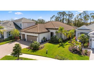 Stunning exterior with lush landscaping, paver driveway, and beautiful tile roof at 11981 Hunters Creek Rd, Venice, FL 34293