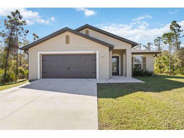 Charming single-story home with a two-car garage, well-manicured lawn, and inviting front entrance at 2721 Burri Ter, North Port, FL 34288