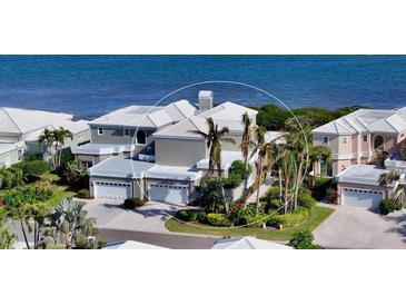 Coastal home featuring a white roof, three-car garage, and lush landscaping with direct access to the beach at 3540 Mistletoe Ln, Longboat Key, FL 34228