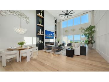Open-concept living room featuring floor-to-ceiling windows, fireplace, modern decor and light wood floors at 3540 Mistletoe Ln, Longboat Key, FL 34228