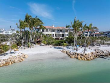 Expansive beachfront estate with pristine sands, turquoise waters, and lush palm trees under a clear, blue sky at 3935 N Shell Rd, Sarasota, FL 34242