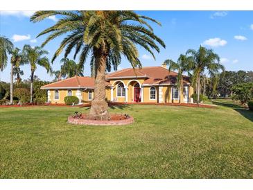 Expansive front yard featuring a well-manicured lawn, mature palm trees, and a charming yellow single-story home at 6107 Glen Abbey Ln, Bradenton, FL 34202