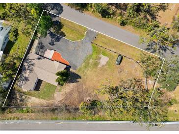 Aerial view of a home with a large lot, a driveway, and mature trees on a sunny day at 7018 13Th E Ave, Bradenton, FL 34208
