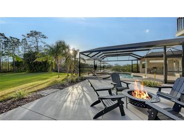Relaxing backyard featuring a fire pit, screened pool, lake view, and lush landscaping at 9818 Old Hyde Park Pl, Bradenton, FL 34202