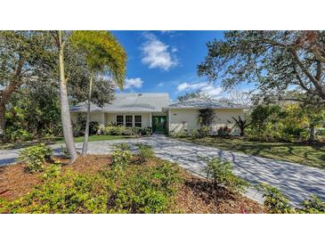 Charming single-story home with a lush front yard, a paved driveway, and a metal roof at 614 Tropical Cir, Sarasota, FL 34242