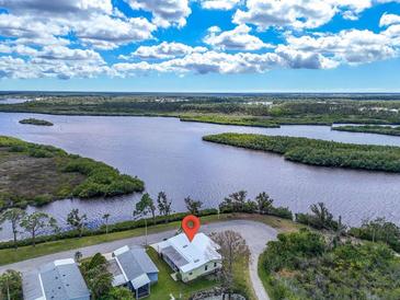 Breathtaking aerial view of the property nestled along the serene waterfront with lush landscaping and clear blue skies at 788 Imperial Dr, North Port, FL 34287