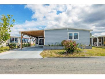Charming single-story home features a light blue exterior, manicured landscaping, and a covered carport at 970 Jolanda Cir, Venice, FL 34285