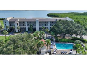 A beautiful aerial view of a white condo community, including a swimming pool surrounded by lush tropical greenery at 4600 Gulf Of Mexico Dr # 202, Longboat Key, FL 34228