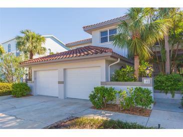 Charming two-story home features a two-car garage, red tile roof, lush landscaping, and a well-maintained exterior at 903 Pinellas Bayway S # 102, St Petersburg, FL 33715