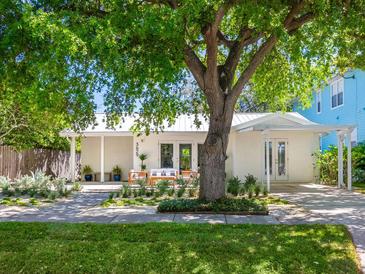 Charming home with a covered porch, white facade, and mature tree providing shade at 3629 Almeria Ave, Sarasota, FL 34239