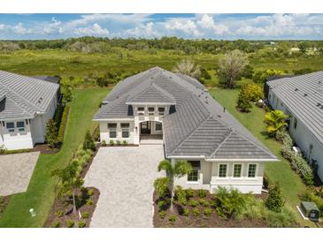 Stunning aerial view of a modern home with lush landscaping and a paver driveway in a serene setting at 8364 Sea Glass Ct, Sarasota, FL 34240