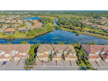 Beautiful aerial view of the tan townhomes with lake and lush green landscaping and community at 1239 Burgos Dr # 305, Sarasota, FL 34238