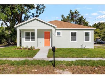 Charming single-story home featuring a bright orange front door, fresh landscaping, and a well-maintained lawn at 1301 12Th S St, St Petersburg, FL 33705