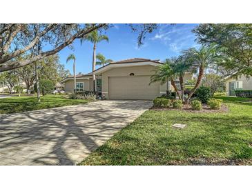 Charming one-story home with a well-manicured lawn, a brick driveway, and a two-car garage at 3016 Highlands Bridge Rd, Sarasota, FL 34235