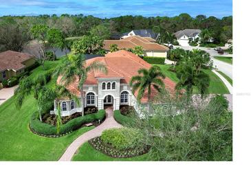 Beautiful home featuring well-manicured lawn and garden, mature palms and barrel tile roof in tropical setting at 7934 Royal Birkdale Cir, Lakewood Ranch, FL 34202