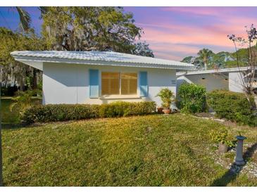 Charming single-story home featuring a well-maintained lawn, white exterior, and bright blue shutters at 1832 University Pl # 23, Sarasota, FL 34235
